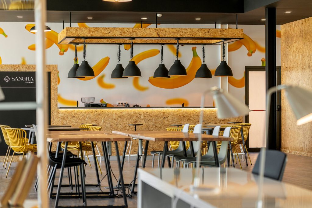 Flexible work tables and kitchenette with yellow mural at Sangha Cowork, Funchal