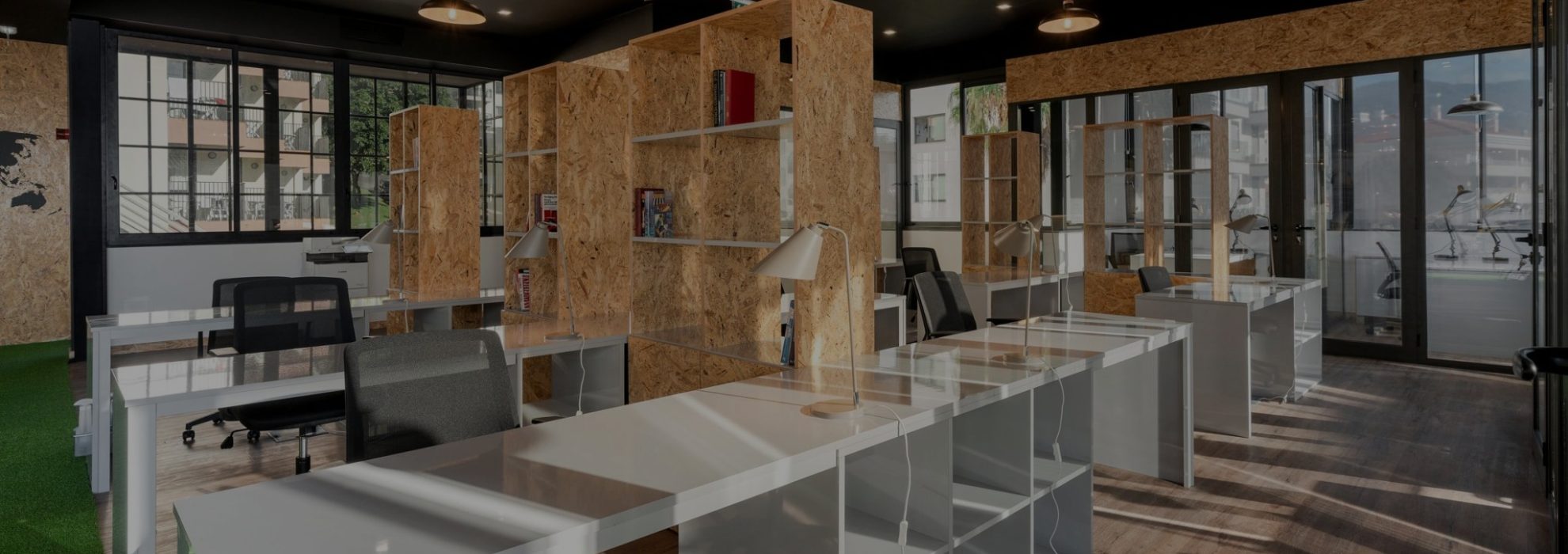 Open-plan coworking space with fixed desks and large windows at Sangha Cowork, Funchal