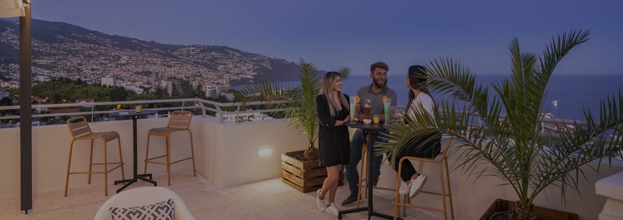Members chatting on the Dorisol rooftop at sunset with a view over Funchal